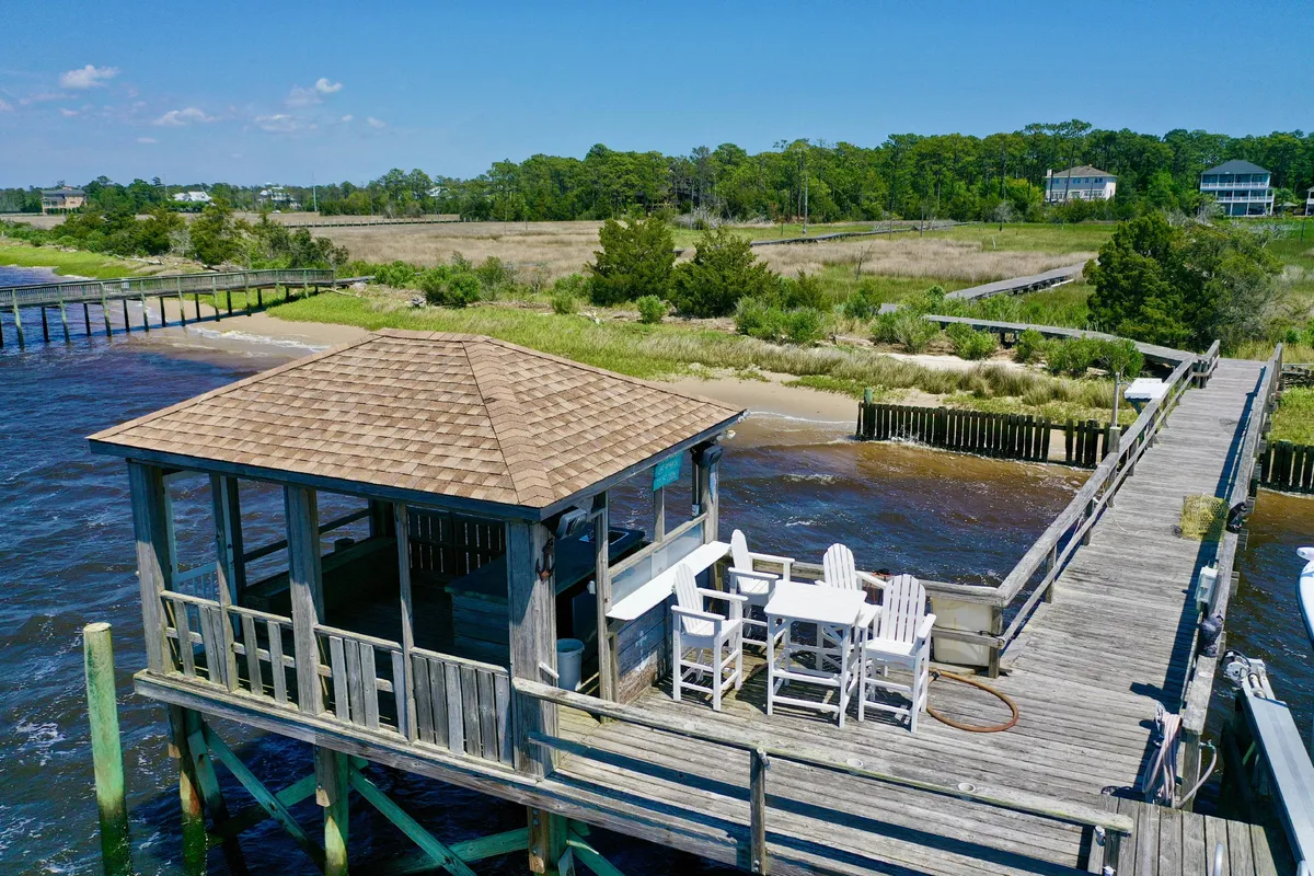 A charming riverside pier with a gazebo, table and chairs, surrounded by greenery and open water. The setting is ideal for couples to enjoy a quiet moment by the water, watch sunsets, have a picnic, or simply relax together in a peaceful environment.