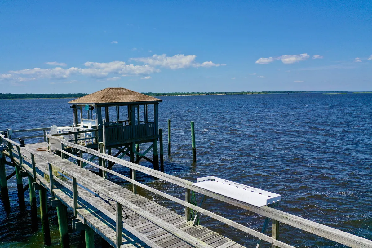 A picturesque wooden pier leading to a gazebo overlooking the calm river waters, with expansive sky views. The pier invites fishing, lounging, and riverside relaxation—offering a peaceful vantage point for sunrise or sunset.