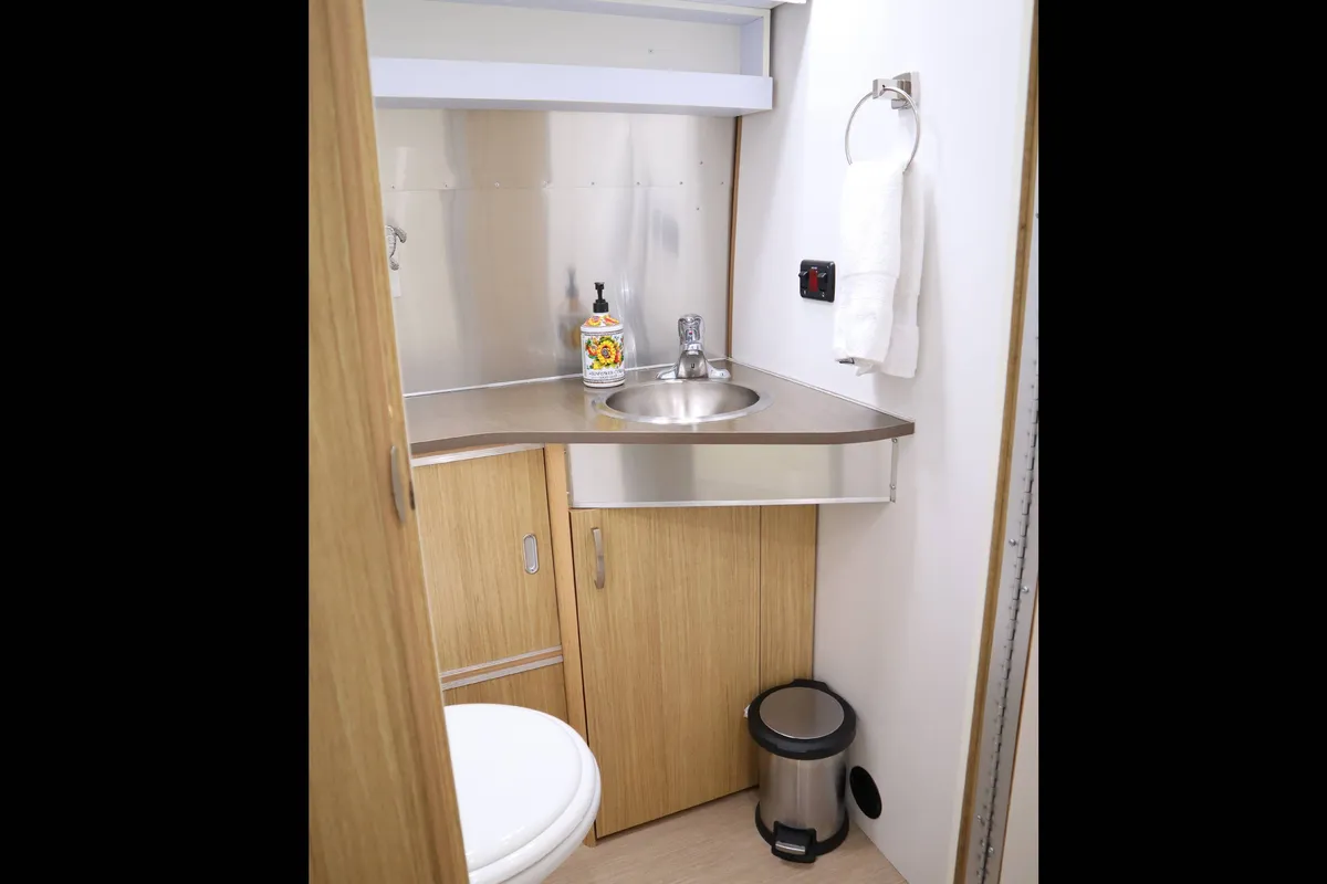 A compact yet thoughtfully designed bathroom with a sink, mirror, toilet, and storage cabinet—tailored for personal grooming and privacy. The fixtures and efficient layout highlight the Airstream’s private bathroom feature.
