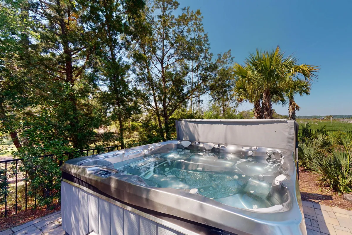 This image features a tranquil hot tub nestled amid lush greenery with a privacy fence, offering an intimate setting for couples to relax and soak while enjoying sunset views. The secluded atmosphere makes it ideal for private moments together, echoing the romantic retreat theme of the section.