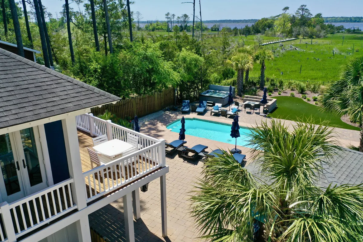 A serene exterior scene showcasing a sparkling swimming pool, comfortable outdoor seating, and lush greenery with a view of the water beyond. The tranquil ambiance invites guests to relax, sunbathe, or take a refreshing dip while surrounded by nature.